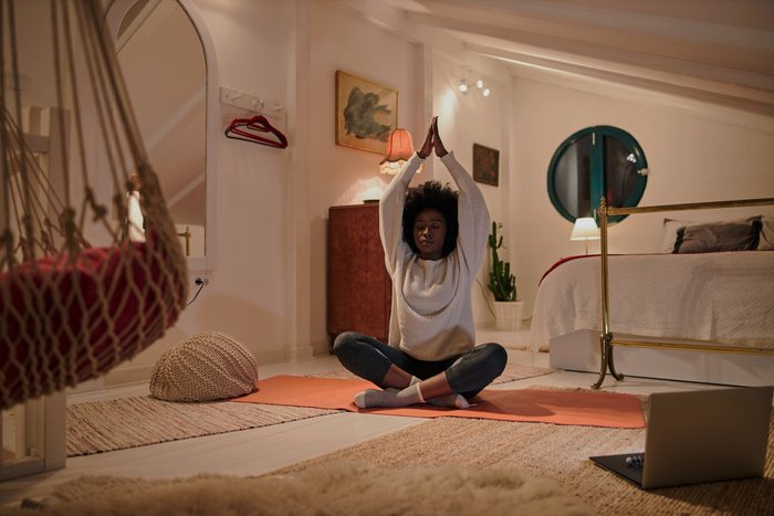 young woman doing yoga and meditation at night in bedroom