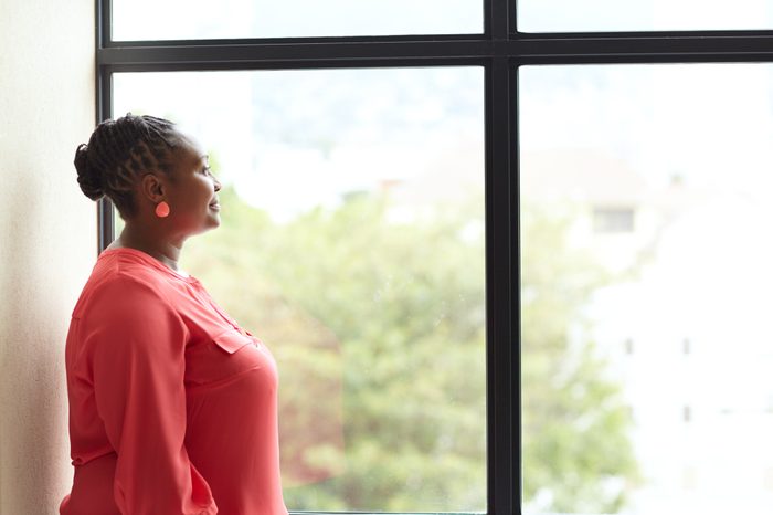 woman looking out the window thinking and taking a deep breath