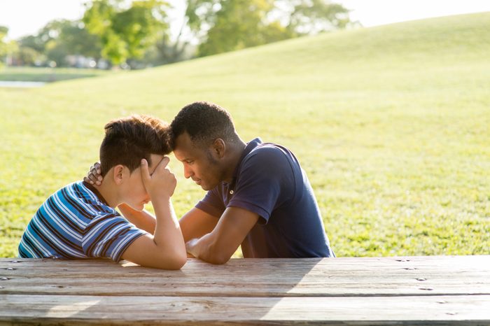 two young med talking at a picnic table in the park