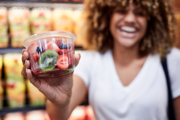 woman holding cup of fruit salad in grocery store
