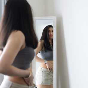 woman looking in mirror not pleased with her reflection