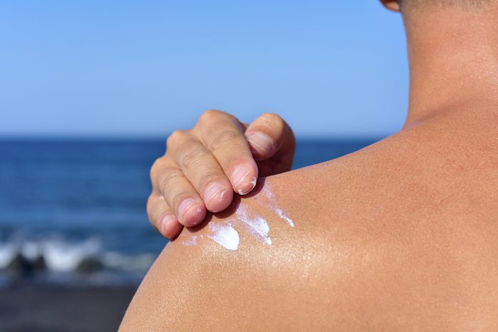 man applying sunscreen to shoulder