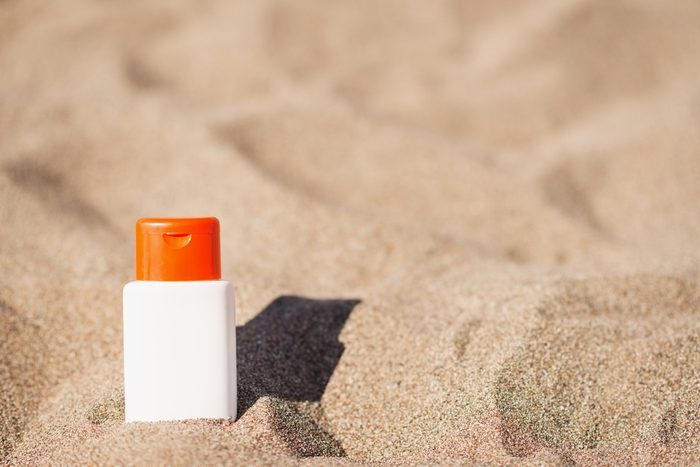 Bottle of sunscreen in the sand