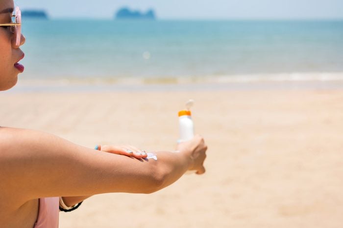 woman applying sunscreen on her arm at the beach