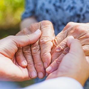 Close up medical doctor holding senior woman's shaking hands, Parkinson disease