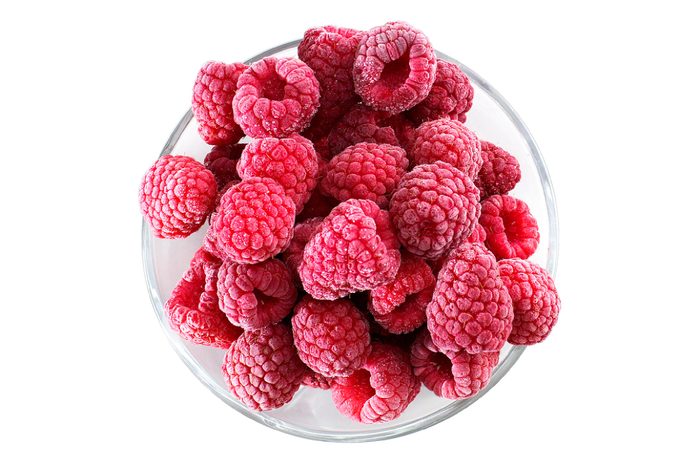 Frozen raspberries in a glass bowl - top view - isolated on white background