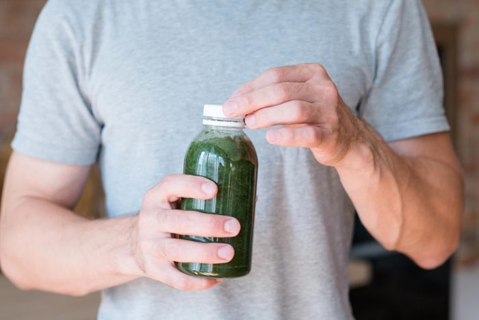 man holding green smoothie in a bottle