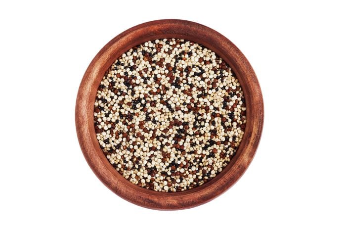 Mixed raw quinoa (Chenopodium quinoa). Red, black and white seeds in wooden bowl isolated on white background