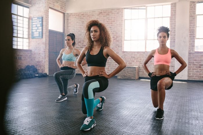 Portrait of young women exercising in aerobics class. Three females doing workout together in gym.