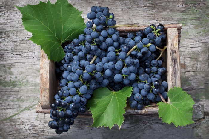 Big clusters of ripe blue grapes in a wooden box