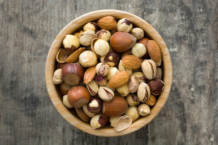 Assorted mixed nuts in bowl on wooden table. Top view