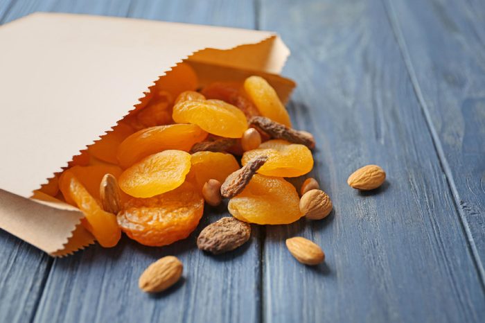 Paper bag with dried apricots and nuts on wooden background