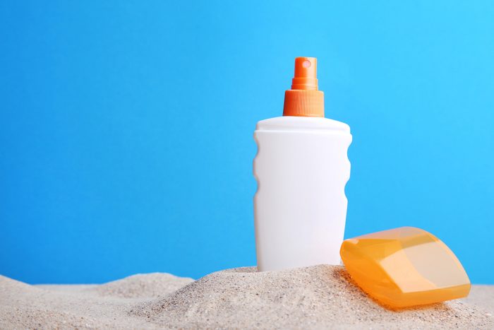 sunscreen bottle propped in sand