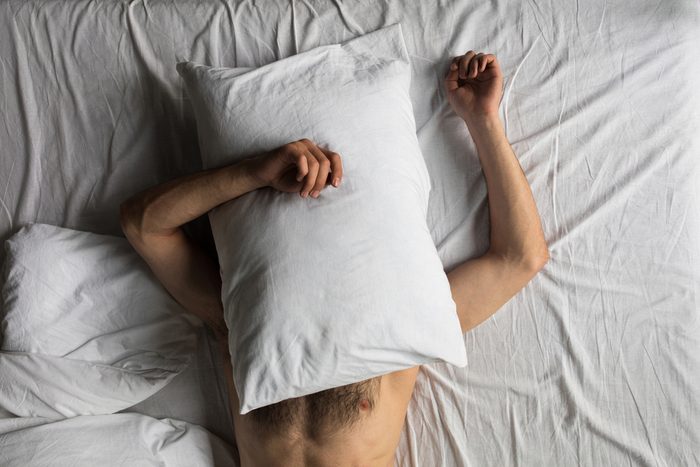 man with pillow over his head