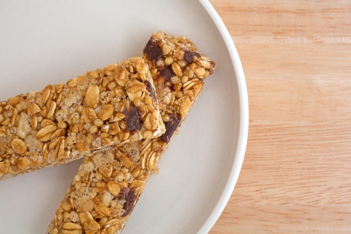 Close view of two chocolate chip granola bars on a plate atop a wood table top.
