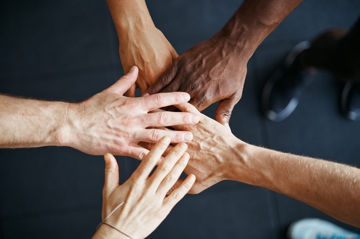 Closeup of a diverse group of people standing in a huddle with their hands together in a gym