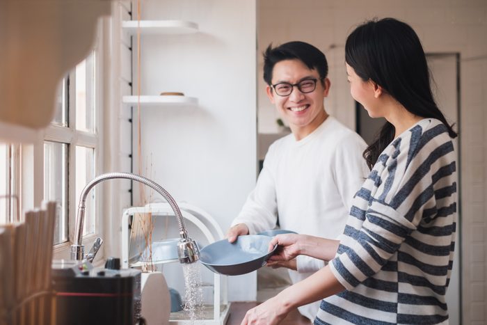 couple washing dishes together in the kitchen