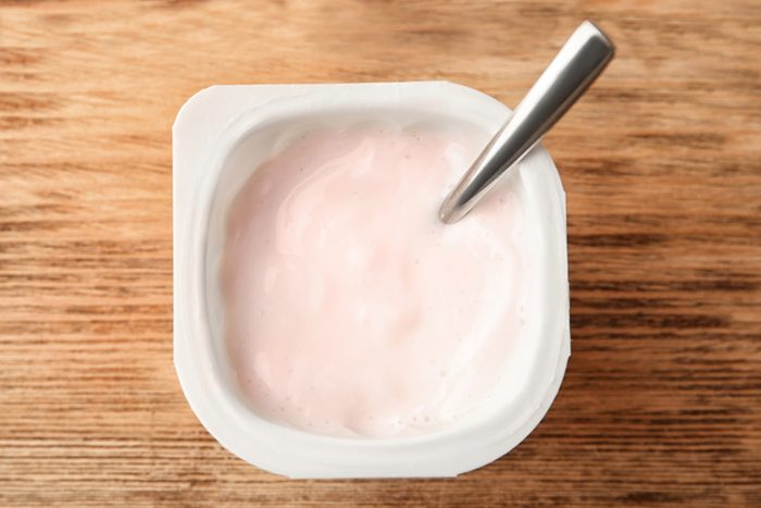 Plastic cup with yummy yogurt on wooden background