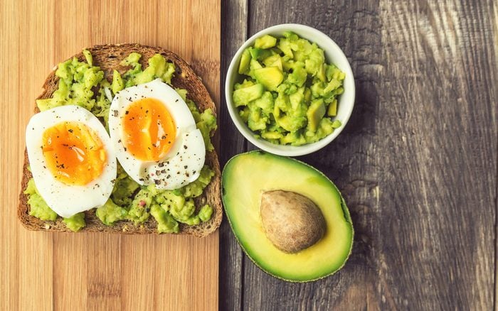 Toast with avocado and egg on rustic wooden background