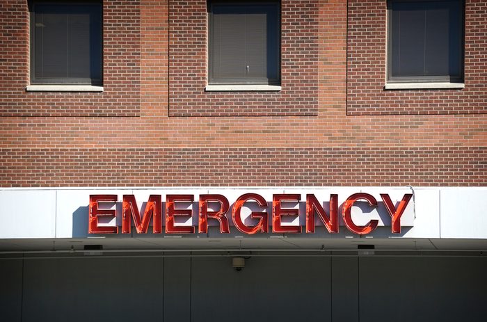 aged and worn vintage photo of neon emergency sign on brick hospital sign 