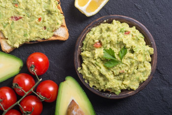 Guacamole with ingredients : avocado , lemon and tomatoes