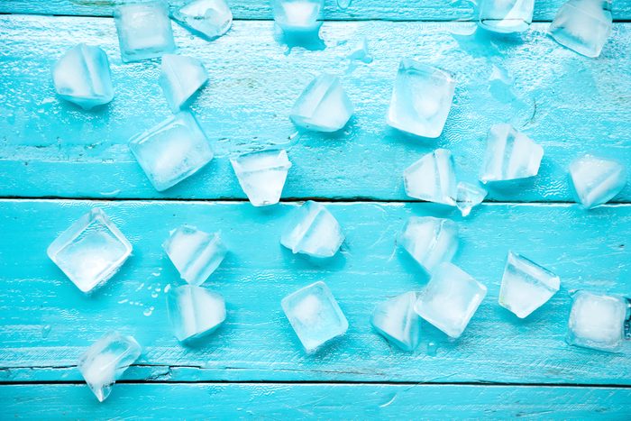 many cold ice cubes on blue wood background