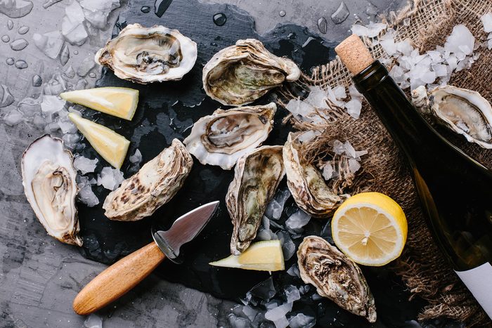 shellfish, lemons and a knife on a wooden cutting board