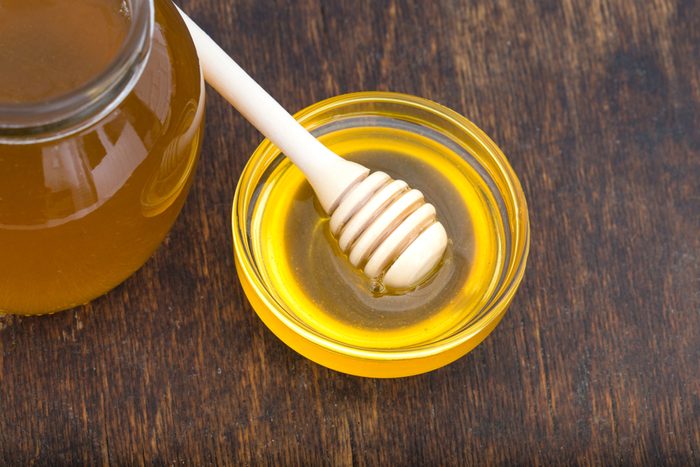Honey with wooden honey dipper on wooden table