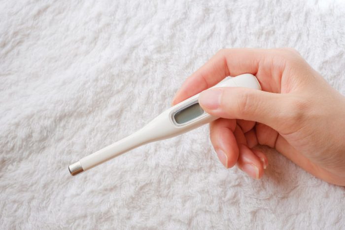 hand holding a white clinical thermometer