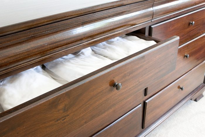 open wooden dresser drawer with white clothing