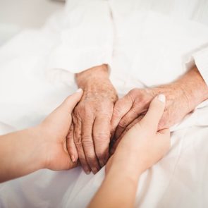 Close-up of senior woman and nurse holding hands