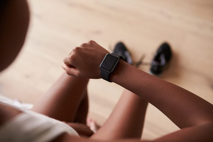 Over-shoulder view of young black woman checking smart watch