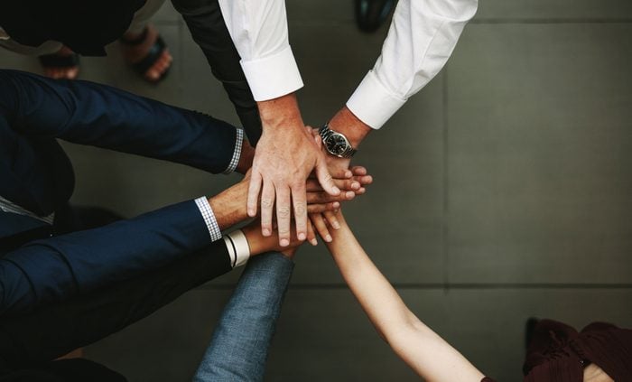 Unity and teamwork Concept. Top view of business people putting their hand together.