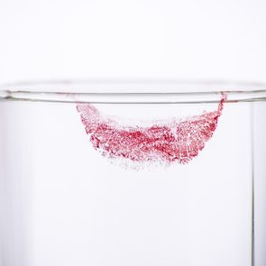 Closeup lipstick on empty glass from woman drink on white background