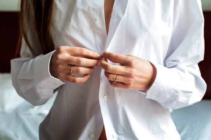 woman's hands buttoning shirt