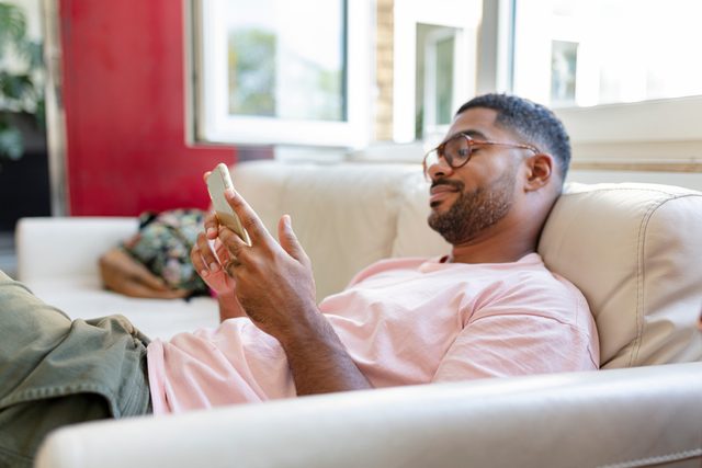 man laying on couch looking at social media on phone