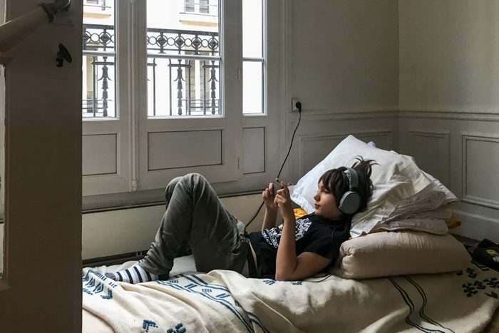 young boy laying in bedroom using smartphone device