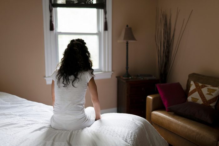 rear view of woman sitting on edge of bed