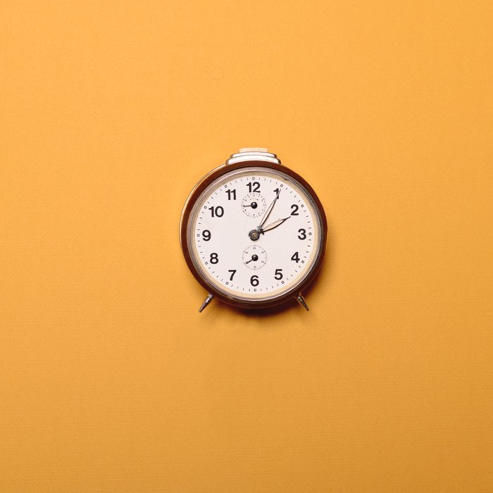 Vintage brown alarm clock on yellow ocher background - Trendy minimal flat lay concept