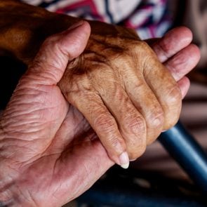 The old man's hand touching the hand of a sick old woman  