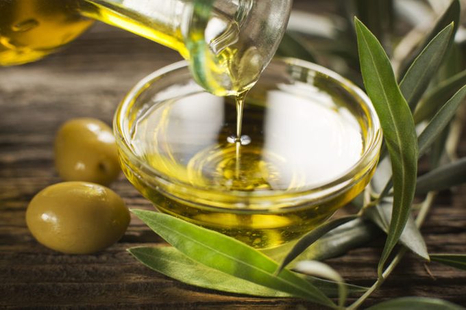 Botella vertiendo aceite de oliva virgen en un cuenco de cerca