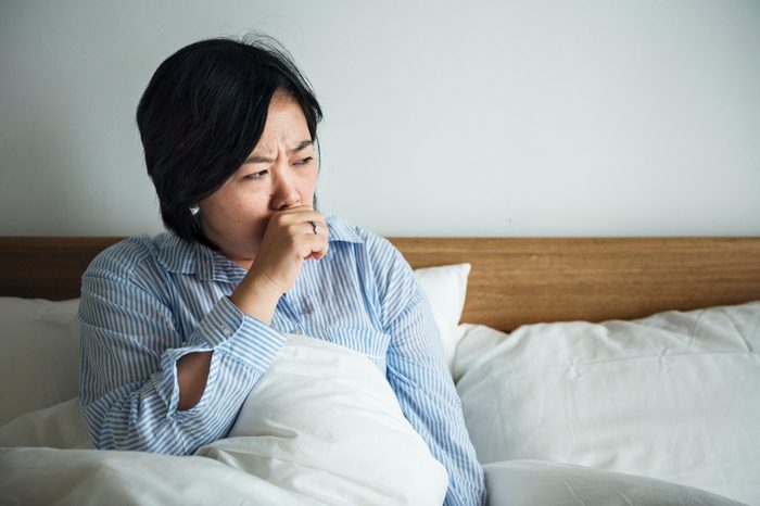 A woman coughing in bed