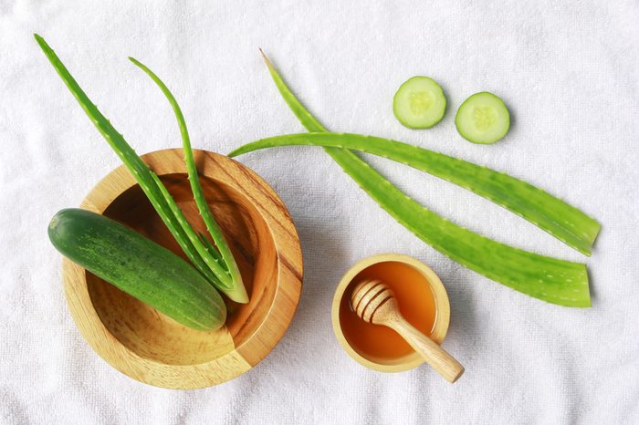 Aloe vera and cucumber with honey on white fabric background