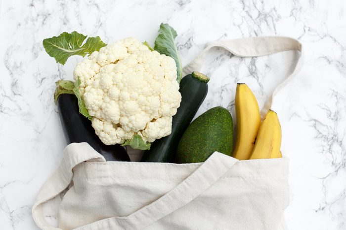 Set of products in a cotton eco bag on a marble table, bananas, avocado, eggplant, zucchini, cauliflower. The concept of zero waste.