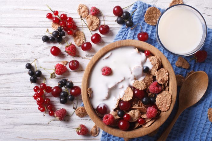 Cereal with milk and fresh berries in a wooden bowl. 