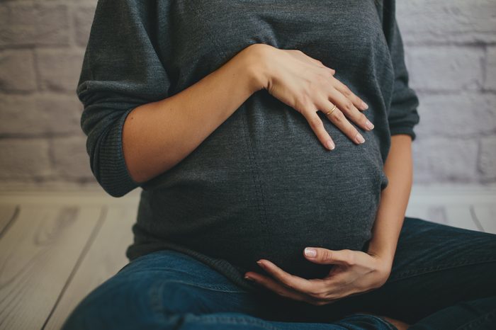 Pregnant woman holds belly