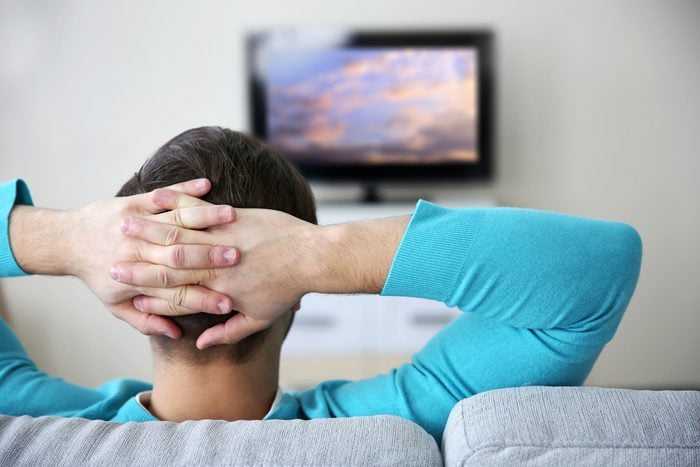 man watching TV on a sofa at home