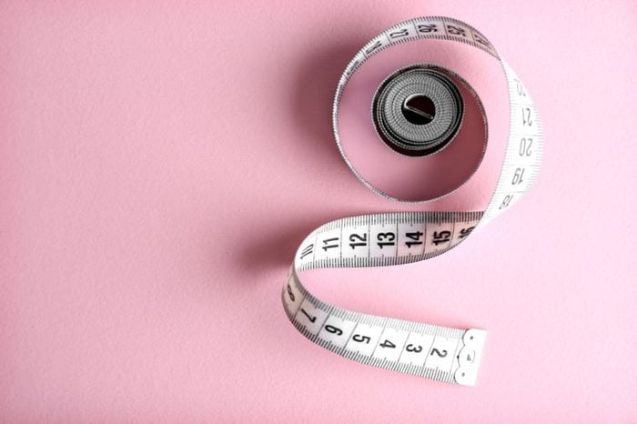 A measuring tape on a pink background.