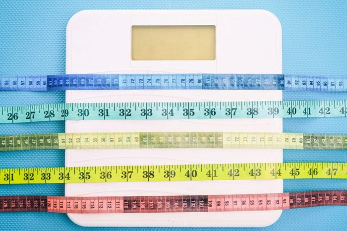Bathroom scale and measure tapes on a blue background.