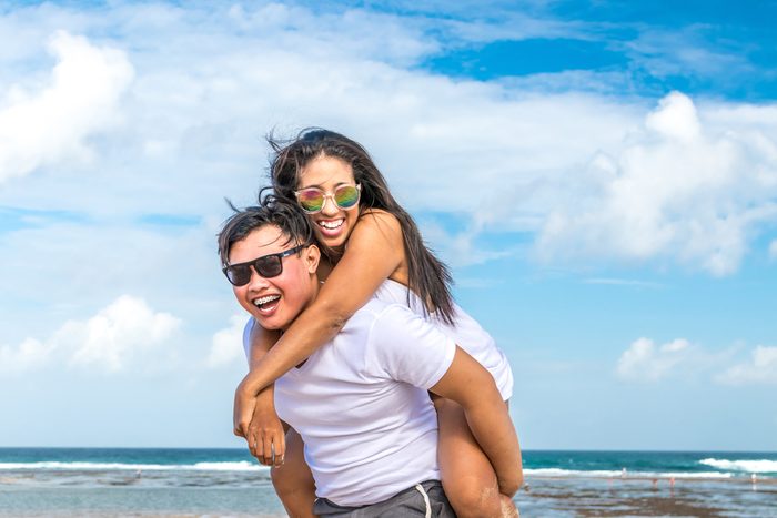 Asian couple having fun on the beach of tropical Bali island, Indonesia.